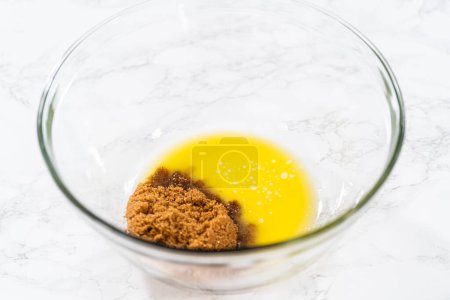 Foto de Mezclar ingredientes húmedos en un tazón de vidrio grande para hornear magdalenas de semillas de amapola de limón. - Imagen libre de derechos