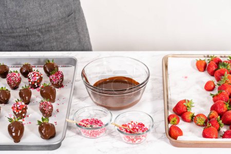 Photo for Dipping strawberries into the melted chocolate to prepare chocolate-covered strawberries. - Royalty Free Image