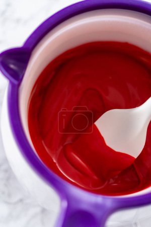 Photo for Melting red chocolate chips in a candy melting pot to make chocolate hearts for chocolate cookies. - Royalty Free Image