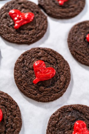Photo for Decorating chocolate cookies with red chocolate hearts. - Royalty Free Image