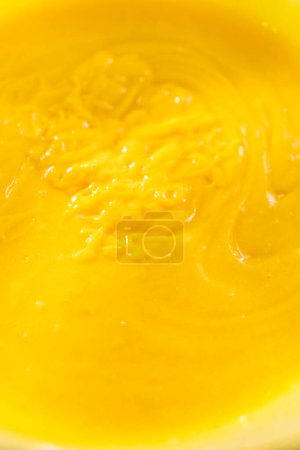 Photo for Mixing ingredients with a hand whisk in a glass mixing bowl to bake a simple vanilla bundt cake. - Royalty Free Image
