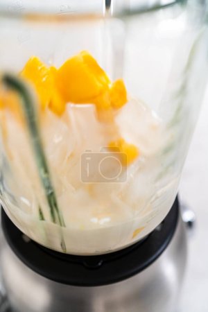 Photo for Mixing ingredients in kitchen blender to prepare mango boba smoothie. - Royalty Free Image