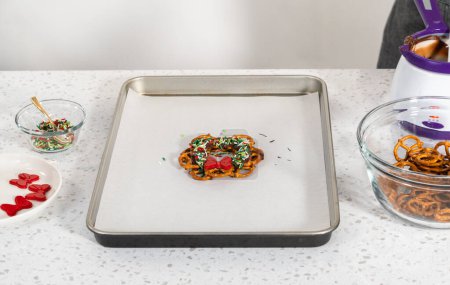 Téléchargez les photos : Dipping pretzels twists into melted chocolate to make a chocolate pretzel Christmas wreath. - en image libre de droit