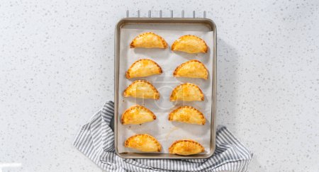 Téléchargez les photos : Flat lay. Freshly baked breakfast empanadas with eggs and sweet potato on the kitchen counter. - en image libre de droit