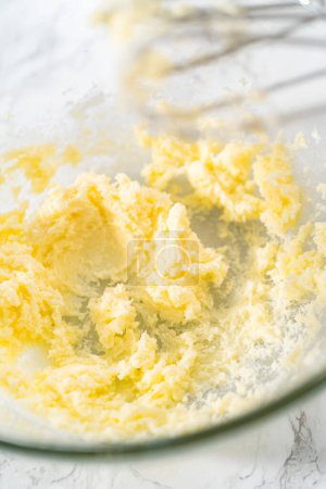 Photo for Mixing ingredients with a hand mixer in a large mixing bowl to bake mini vanilla cupcakes with ombre pink buttercream frosting. - Royalty Free Image