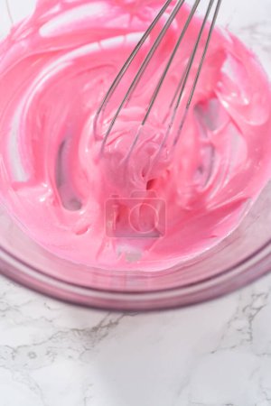 Foto de Mezclar colorante de comida rosa en el merengue para hornear galletas de merengue de Pascua. - Imagen libre de derechos