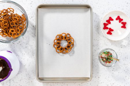 Photo for Flat lay. Dipping pretzels twists into melted chocolate to make a chocolate pretzel Christmas wreath. - Royalty Free Image