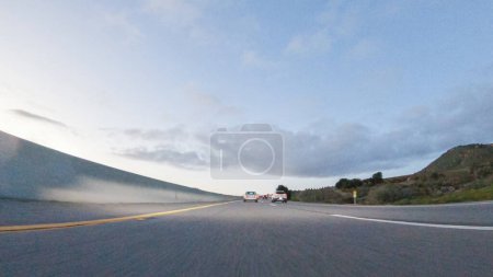 Photo for As the sun sets, driving on HWY 101 near Pismo Beach, California becomes a captivating experience with the sky painted in shades of orange and pink, casting a warm glow over the coastal landscape. - Royalty Free Image
