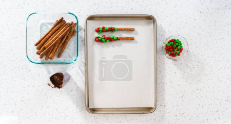 Foto de Denver, Colorado, Estados Unidos-18 de diciembre de 2022-Flat lay. Sumergiendo barras de pretzel en chocolate derretido y rociando caramelos para hacer barras de pretzel cubiertas de chocolate. - Imagen libre de derechos