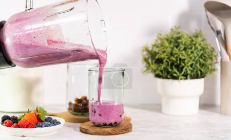 Foto de Pouring freshly made mixed berry boba smoothie into a drinking glass. - Imagen libre de derechos