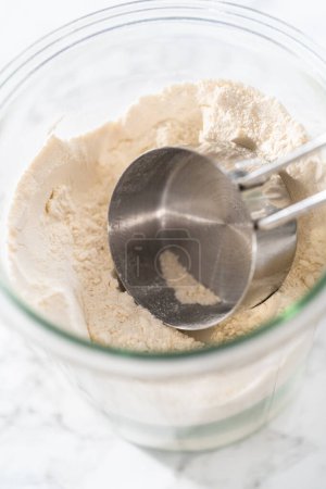 Photo for Measuring cup inside glass jar filled with all-purpose flour. - Royalty Free Image