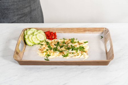 Téléchargez les photos : Disposer des légumes frais et marinés sur un plateau de service pour préparer une planche de beurre végétarienne pour une fête. - en image libre de droit