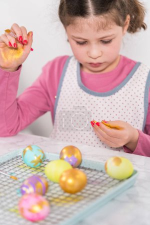Photo for Easter egg coloring. Painting Easter eggs with gold luster. - Royalty Free Image