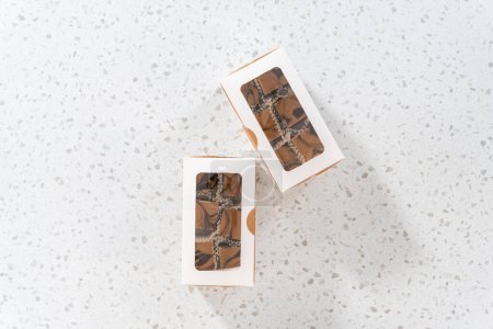 Téléchargez les photos : Pose plate. Emballage de caramel au chocolat fait maison avec du beurre d'arachide tourbillonner dans une boîte cadeau blanche. - en image libre de droit