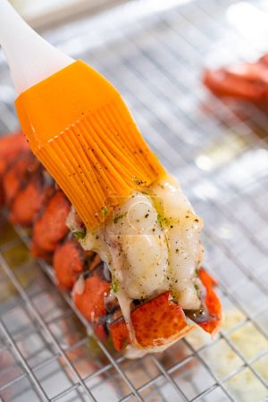 Photo for Buttering lobster tails on a baking sheet with kitchen foil. - Royalty Free Image