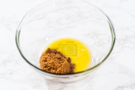 Téléchargez les photos : Mélanger les ingrédients humides dans un grand bol à mélanger en verre pour faire cuire des muffins de graines de pavot citron. - en image libre de droit