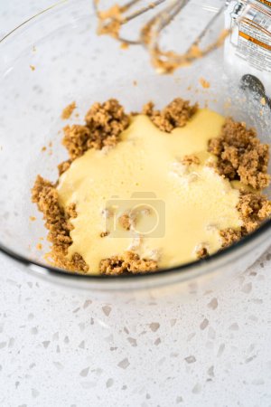 Téléchargez les photos : Mélanger les ingrédients avec un mélangeur à main dans un grand bol à mélanger pour cuire des cupcakes dulce de leche. - en image libre de droit