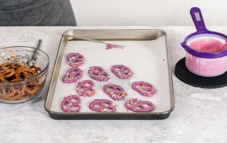 Foto de Dipping pretzels twists into melted chocolate to make mermaid pretzel twists. - Imagen libre de derechos