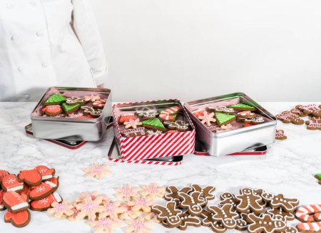 Téléchargez les photos : Emballage d'une variété maison de biscuits au caramel et au pain d'épice pour les cadeaux alimentaires de Noël dans des boîtes d'étain. - en image libre de droit