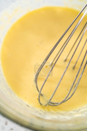 Téléchargez les photos : Mélange d'ingrédients humides dans un petit bol à mélanger en verre pour cuire des cupcakes dulce de leche. - en image libre de droit