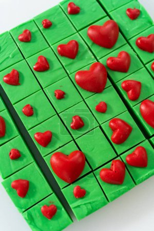 Foto de Acostado. Fudge verde casero con corazones rojos piezas cuadradas en un mostrador de cocina. - Imagen libre de derechos
