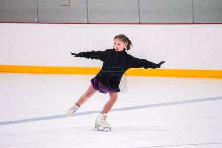 Foto de Niña practicando antes de su competición de patinaje artístico en la pista de hielo interior. - Imagen libre de derechos