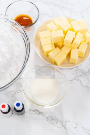 Foto de Ingredientes medidos en cuencos de vidrio para hacer glaseado de crema de mantequilla para mini cupcakes de bandera estadounidense. - Imagen libre de derechos