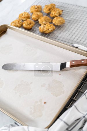 Téléchargez les photos : Refroidissement de noix de macadamia au chocolat blanc fraîchement cuites sur un comptoir de cuisine. - en image libre de droit