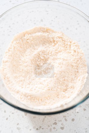 Foto de Mezclar ingredientes secos con un batidor de mano en un tazón grande de vidrio para hornear un simple pastel de vainilla. - Imagen libre de derechos