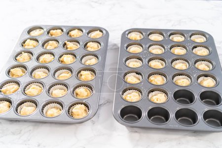 Photo for Scooping cupcake batter with dough scoop into a baking pan with liners to bake American flag mini cupcakes. - Royalty Free Image