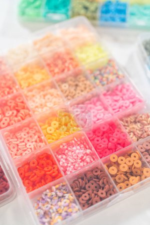 Téléchargez les photos : Assortiment de boîtes de perles d'argile soigneusement disposées sur une table blanche, en attendant un projet créatif d'artisanat pour enfants. - en image libre de droit