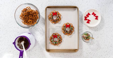 Téléchargez les photos : Flat lay. Dipping pretzels twists into melted chocolate to make a chocolate pretzel Christmas wreath. - en image libre de droit