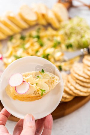Téléchargez les photos : Trancher la baguette française avec du beurre aromatisé et du radis. - en image libre de droit