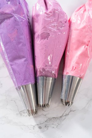 Téléchargez les photos : Glaçage crème beurre rose Ombre dans un sac de tuyauterie avec une pointe de tuyauterie en métal jumbo. - en image libre de droit