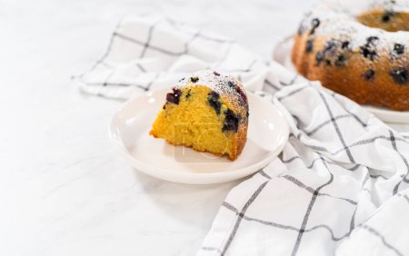 Photo for Slicing freshly baked lemon blueberry bundt cake with powdered sugar dusting. - Royalty Free Image