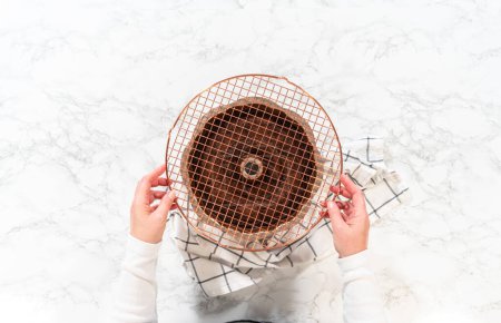 Photo for Flat lay. With precision, the Chocolate Bundt Cake is carefully removed from the pan - placed onto a round cooling rack, preparing it for a flawless presentation and delightful indulgence. - Royalty Free Image