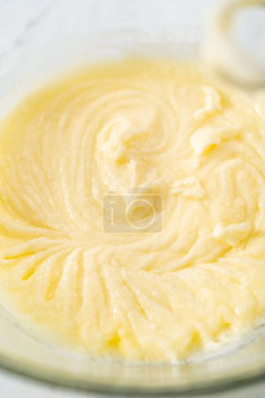Téléchargez les photos : Mélanger les ingrédients humides dans un grand bol à mélanger en verre pour faire cuire le gâteau bundt aux myrtilles au citron. - en image libre de droit