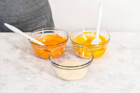 Foto de Mezcla de naranja y amarillo colorante de alimentos en chocolate derretido para preparar caramelo de maíz fudge. - Imagen libre de derechos
