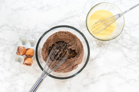 Photo for Flat lay. In the process of creating mouthwatering chocolate cupcakes, the first step involves meticulously mixing the ingredients in a glass mixing bowl to make the perfect batter. - Royalty Free Image