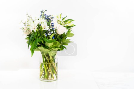 Téléchargez les photos : Un magnifique bouquet de roses blanches fraîches et de fleurs assorties disposées gracieusement dans un vase, exsudant une beauté intemporelle. - en image libre de droit