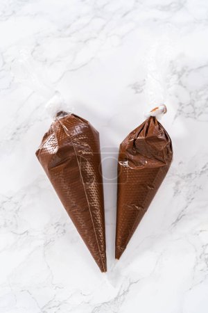 Téléchargez les photos : Chocolat fondu dans des sacs de tuyauterie préparés pour le glaçage biscuits sablés en forme de panda. - en image libre de droit