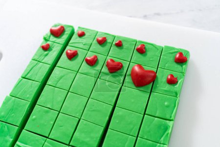 Téléchargez les photos : Décoration de morceaux carrés de caramel vert avec des cœurs rouges chocolat. - en image libre de droit