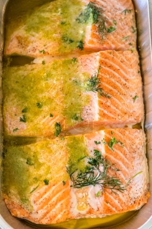 Photo for Discover the mouthwatering journey of salmon as its cooked to perfection in an oven, nestled in a foil tray, adorned with rich butter and tantalizing spices. - Royalty Free Image