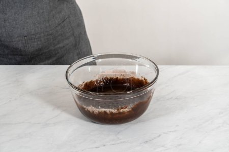 Téléchargez les photos : Mélanger les ingrédients secs et humides avec un fouet à la main dans un bol de mélange en verre pour cuire des brownies à la menthe poivrée. - en image libre de droit