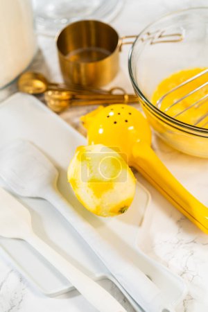 Téléchargez les photos : Intégrer les ingrédients dans un bol en verre, en remuant adepte avec un fouet pour confectionner un gâteau de bundt citron-myrtille alléchant. - en image libre de droit