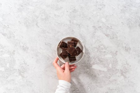 Photo for Flat lay. Homemade chocolate macadamia fudge square pieces on a white plate. - Royalty Free Image