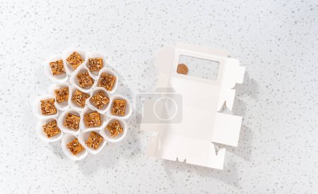 Photo for Flat lay. Packaging homemade pumpkin spice fudge with pecans into a white paper gift box. - Royalty Free Image