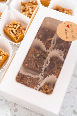 Foto de Embalaje de caramelo de especias de calabaza casera con pacanas en una caja de regalo de papel blanco. - Imagen libre de derechos