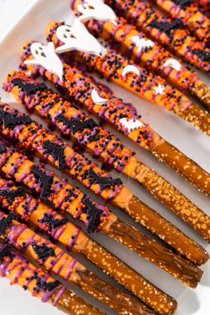 Photo for Halloween chocolate-covered pretzel rods with sprinkles on a white serving plate. - Royalty Free Image
