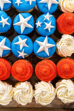 Foto de Arranging mini vanilla cupcakes in the shape of the American flag. - Imagen libre de derechos